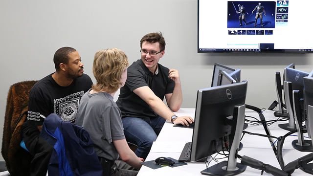 Three students collaborate on a gaming project.