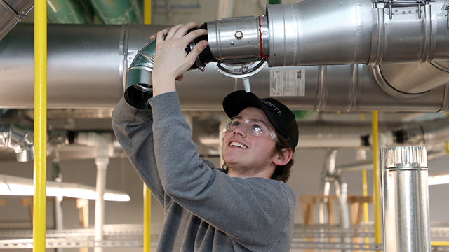 An HVAC student assembles some ductwork.