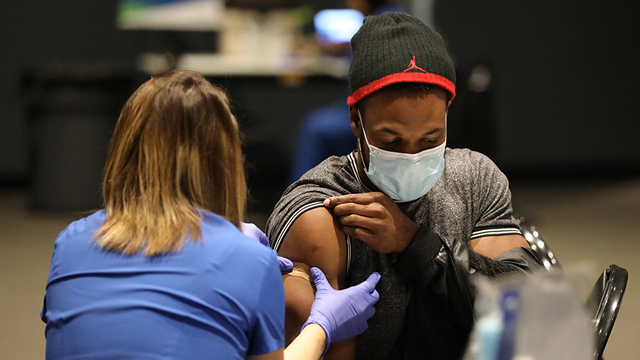 A nurse puts a bandage on a man's arm after giving a COVID vaccination.
