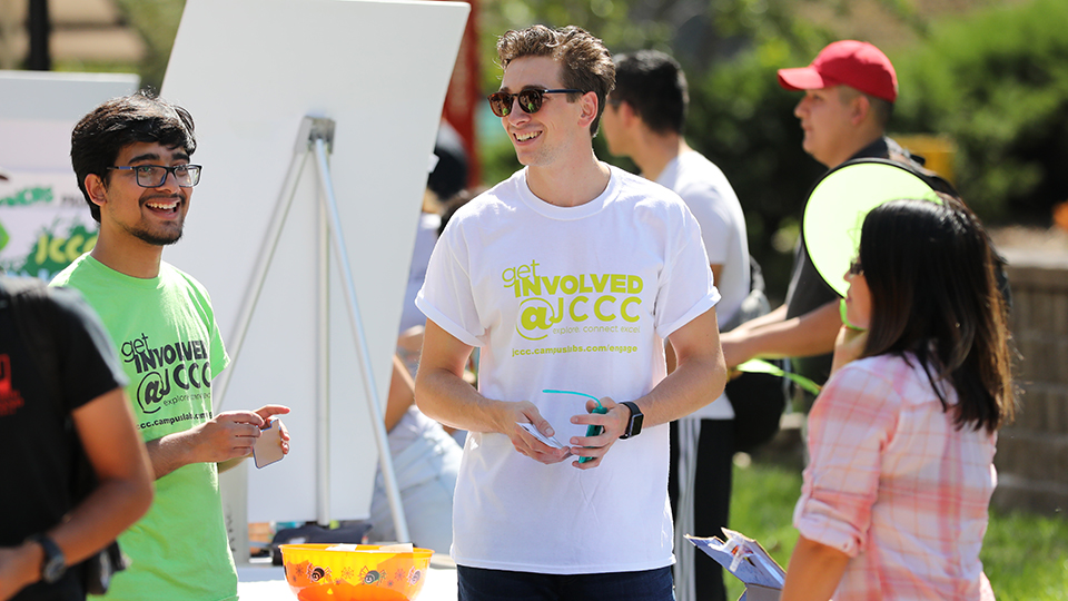 Students wearing "Get Involved at JCCC" shirts and chatting at an outdoor event