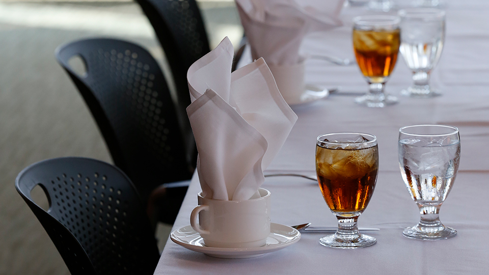 A table set for formal dining with glasses of water and iced tea.