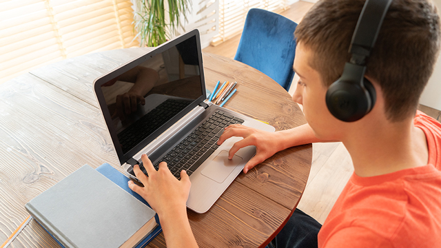 A boy works on a computer on a table at home.