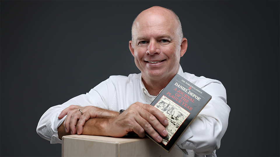 Jim McWard holding a copy of the book "Journal of the Plague Year"