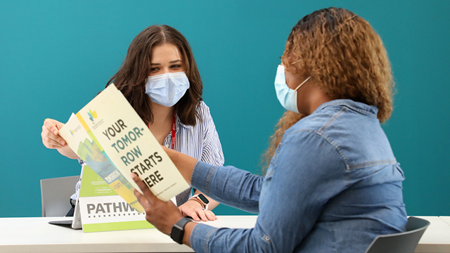 Two women discuss JCCC promotional materials.