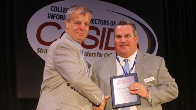 At a recent convention in Orlando, CoSIDA president Andy Seeley (left) presented the organization’s 25-year award to Tyler Cundith, Johnson County Community College sports information director. Contributed photo.