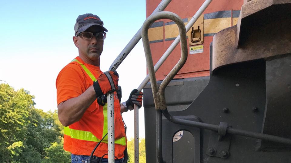 Greg Ambuehl posing on a metal ladder going up to a railroad car