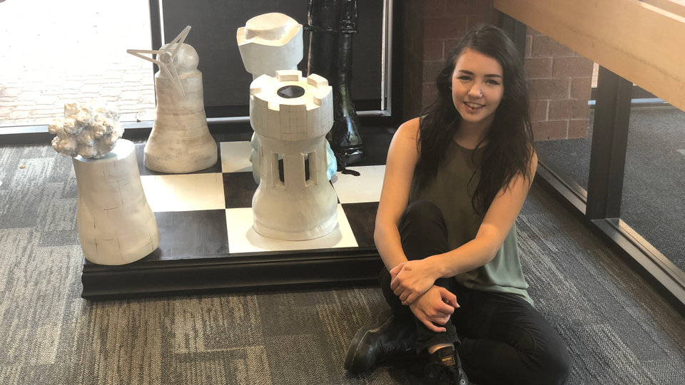 Arianna Michaelson posing with her indoor chess sculpture