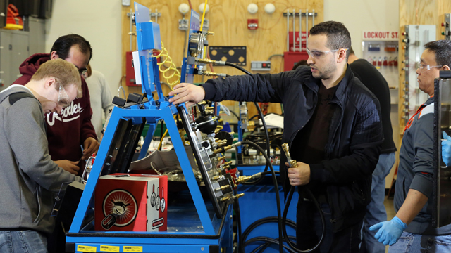 Students in the electronics lab working on a hydraulic and pneumatic console