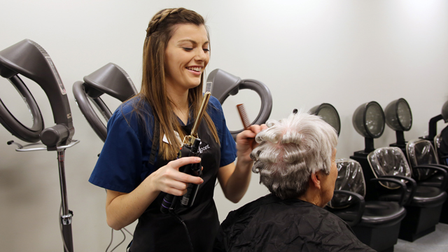 A cosmetology student styling a client's hair