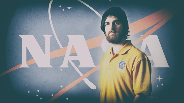 Isaac Jambor standing in front of a backdrop of the NASA logo
