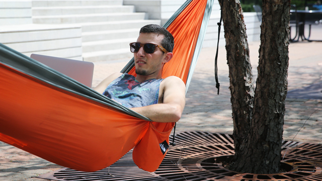 Student relaxing while studying in a hammock set up in the COM courtyard.
