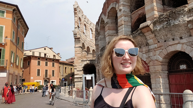 Chelsey Davis stands in front of ruins in an Italian city