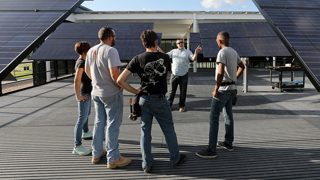 Students listening to a lecture among the solar panels outside the CTEC building.