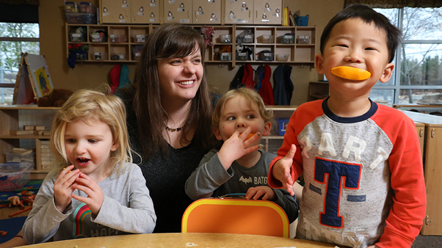Jennie Brockhoff reacts to the silliness of orange slice smiles during snack time with her childcare kids.