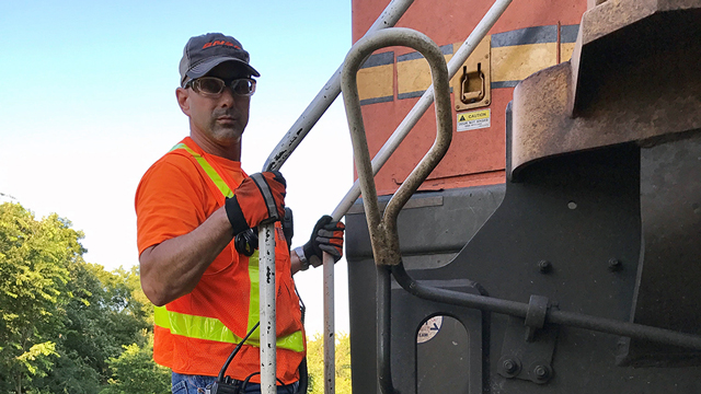 Marines veteran and railroad conductor student Greg A. holds the rails on a stationary NARS program train.