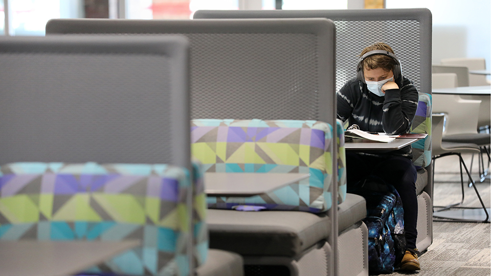 Student wearing a face mask studying in the newly remodeled library space