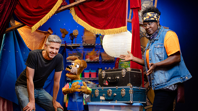 Alex and Da'Lene, humans and co-owners of the Mesner Puppet Theatre, interact with their puppet friend.