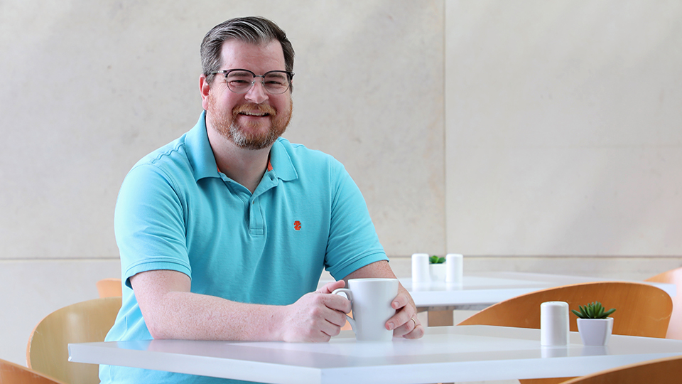 Todd Sitcler sits at table in Cafe Tempo with cup of coffee.