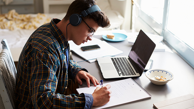 Student wearing headphones studying with a laptop