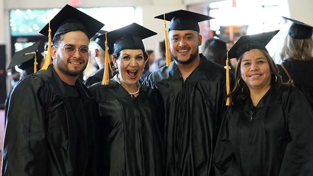 Four GED students wearing graduation caps and gowns.