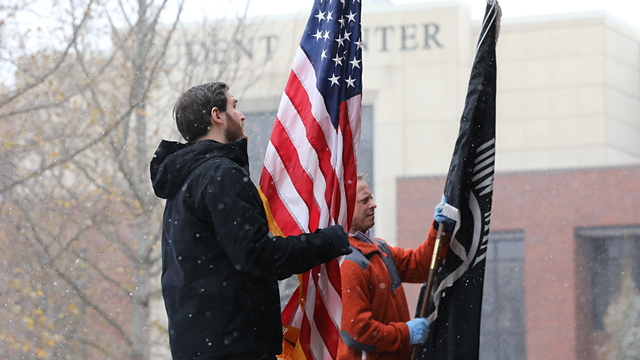 Two student veterans raising an American flag