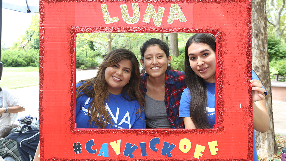 Three Hispanic students posing with a LUNA poster during Cav Kickoff