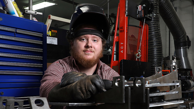 Colby Bunch sitting among tools in the welding lab