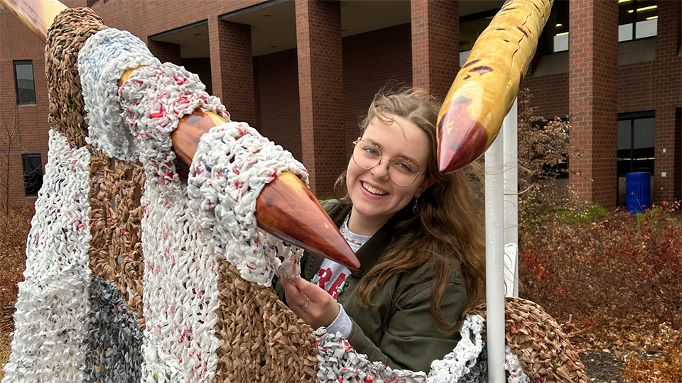 Alayna Reinke posing with her sustainability sculpture