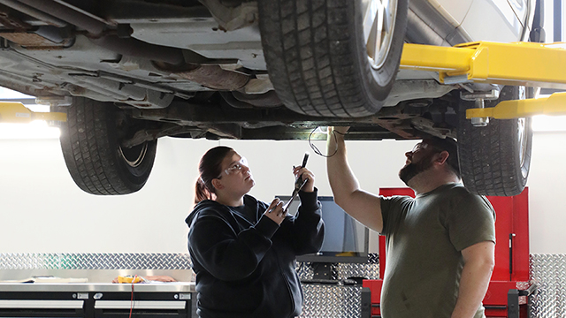 Female student working with instructor in the automotive lab