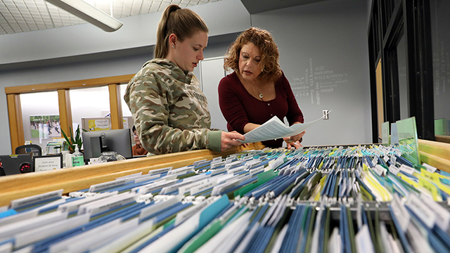 Student and career development staff member looking into a file cabinet.