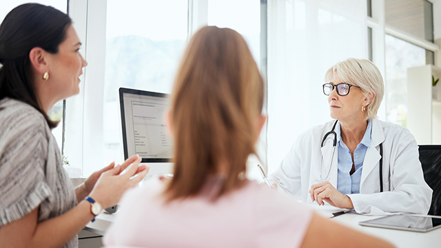 A patient with her interpreter conversing with a physician