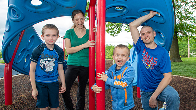 Tyler Pennington under a brightly colored tent with his wife and two young sons