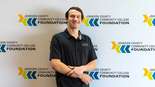 Josh Filley standing in front of a backdrop with JCCC logos on it