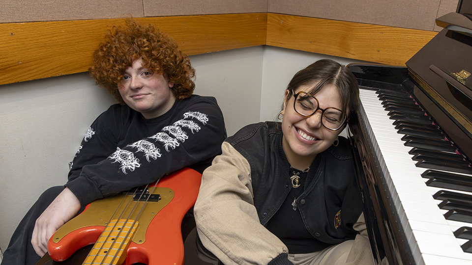 Tobias Oleary and Sofia Ortiz sitting on the floor by a piano