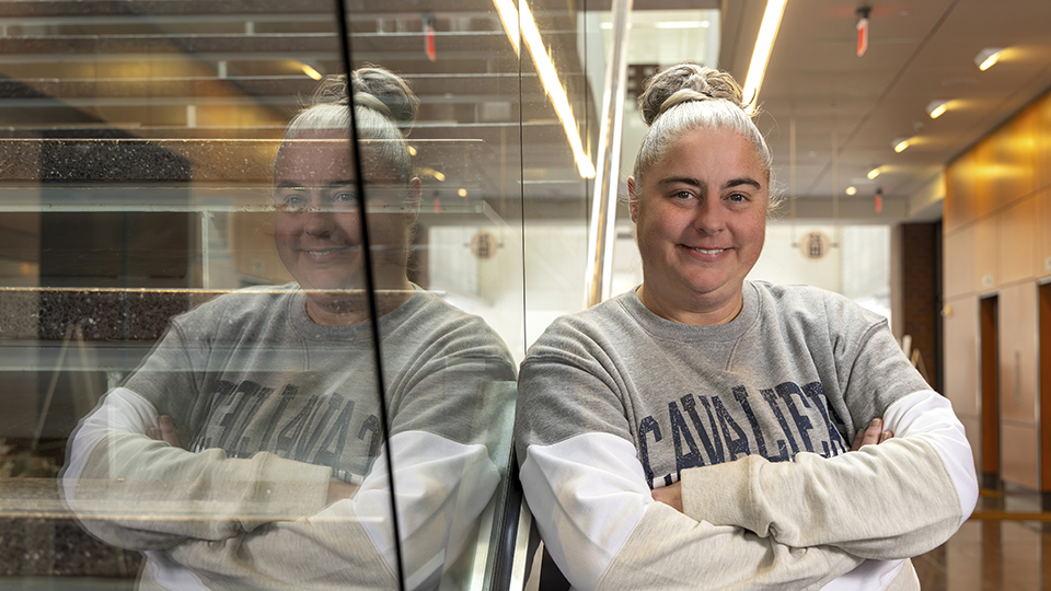 A smiling Raina Lupton is leaning against the stairway in the Regnier Center