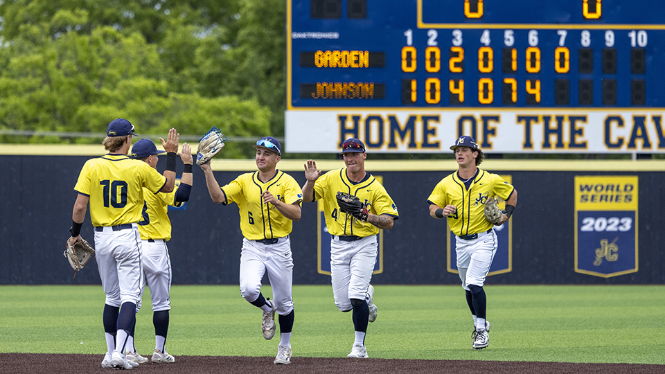JCCC cavaliers baseball players on the field with the scoreboard in the background