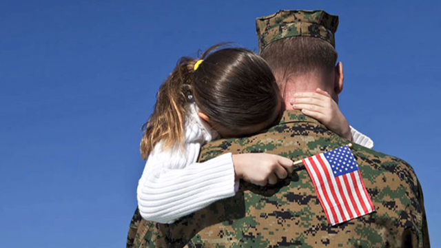 a young girl holding a flag hugs a soldier