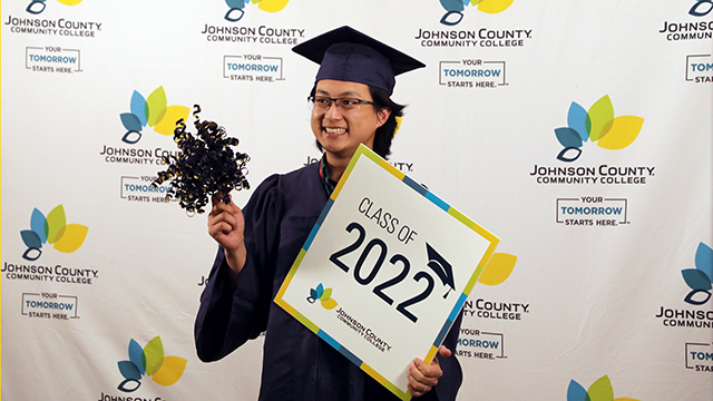 A JCCC graduate holds up a sign that says Class of 2022