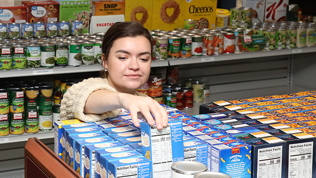 A worker stocks the shelves with nonperishable foods at the Student Basic Needs Center