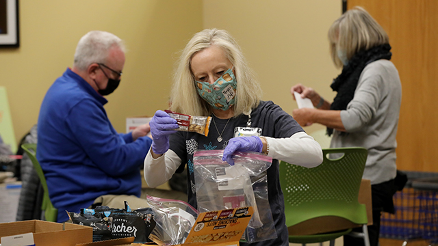 A group of 3 JCCC retirees work on packing hygiene products for a holiday giving drive