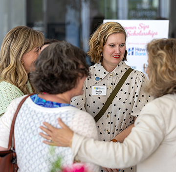 a group of women greet each other at the sips and scholarships event