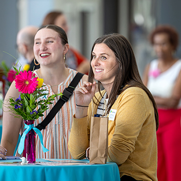 a group of women smile and chat over wine at the 2025 Summer Sips and Scholarships event