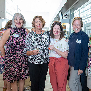 a group of women standing in a row and smiling at the viewer