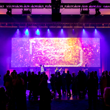 a crowd of people silhouetted against the stage lights at the 2024 SEE gala