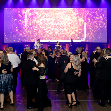 gala attendees dancing while a live band performs on stage