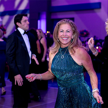 a smiling woman dancing at the 2025 Some Enchanted Evening Gala