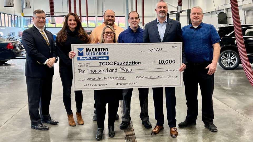 Joy Ginsburg from the JCCC Foundation stands with President Andy Bowne and accepts a check from employees of McCarthy Auto Group.