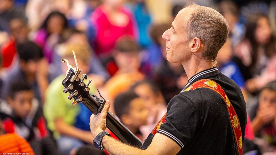 Billy Jonas playing guitar in front of a large crowd