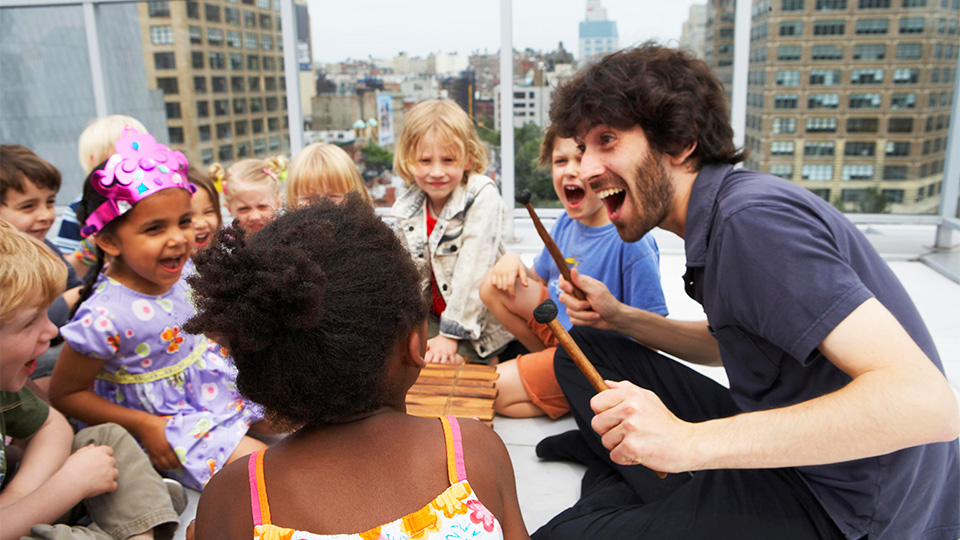 Oran Etkin sitting with a group of young children who are participating in a music lesson