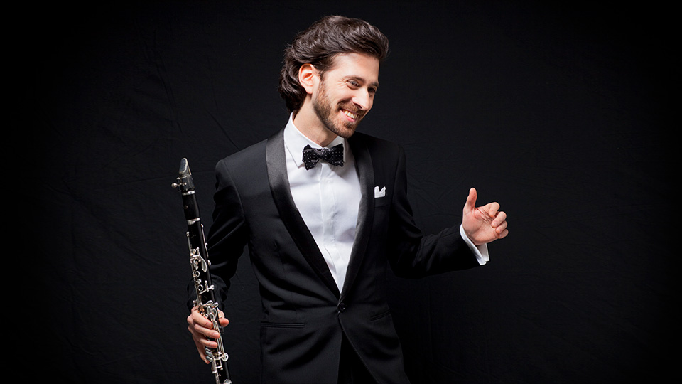 Oran Etkin holding a clarinet and smiling